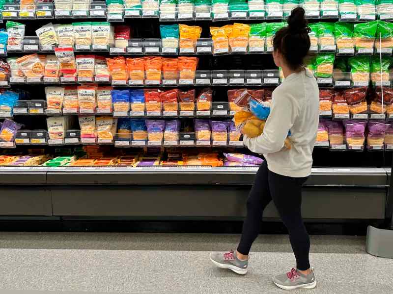 A woman browsing different cheese products in a grocery store