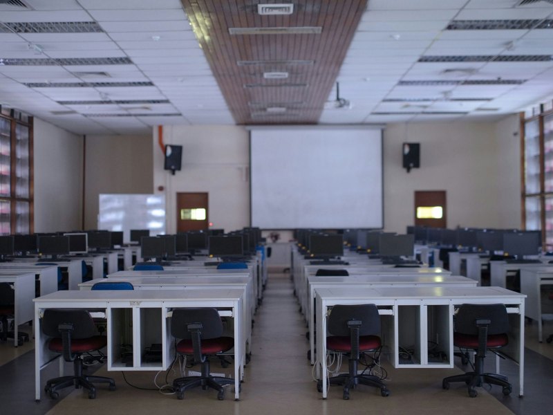 An empty classroom with rows of chairs, desks and computers