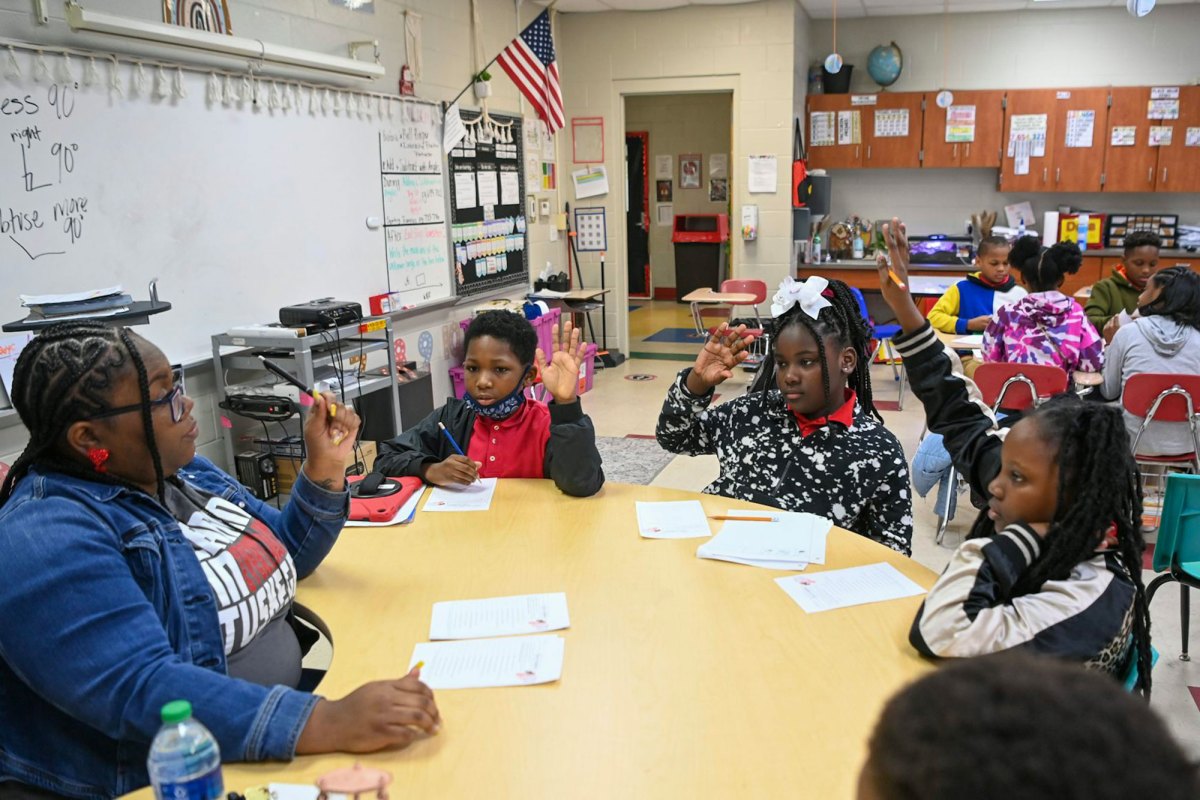 An elementary classroom, focusing on five students seated around a circular table with the teacher