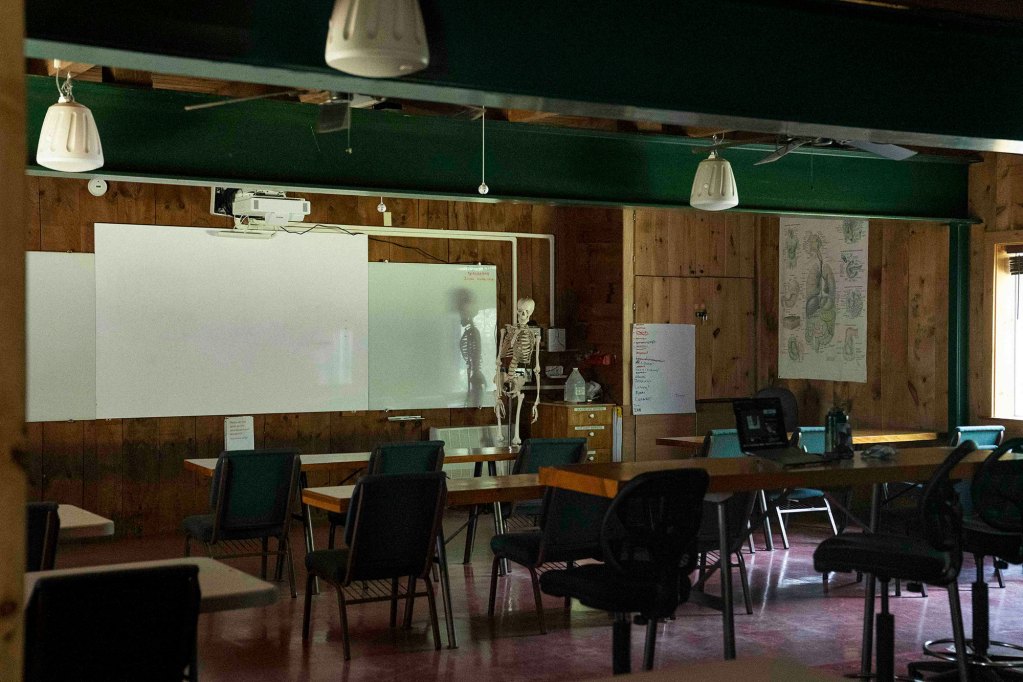 An empty classroom with desks, chairs and whiteboard