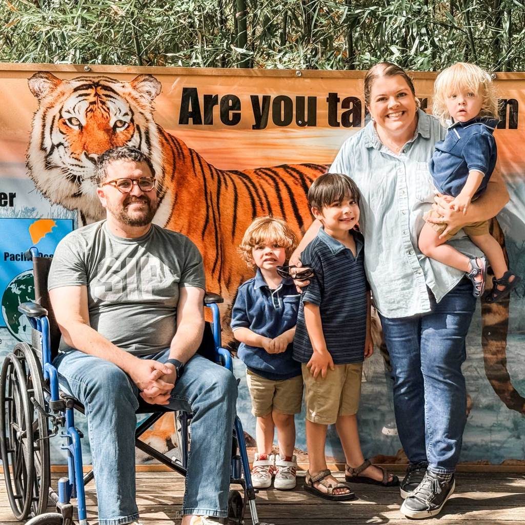 Ben Floyd, in wheelchair, sits beside his wife and two children at a zoo