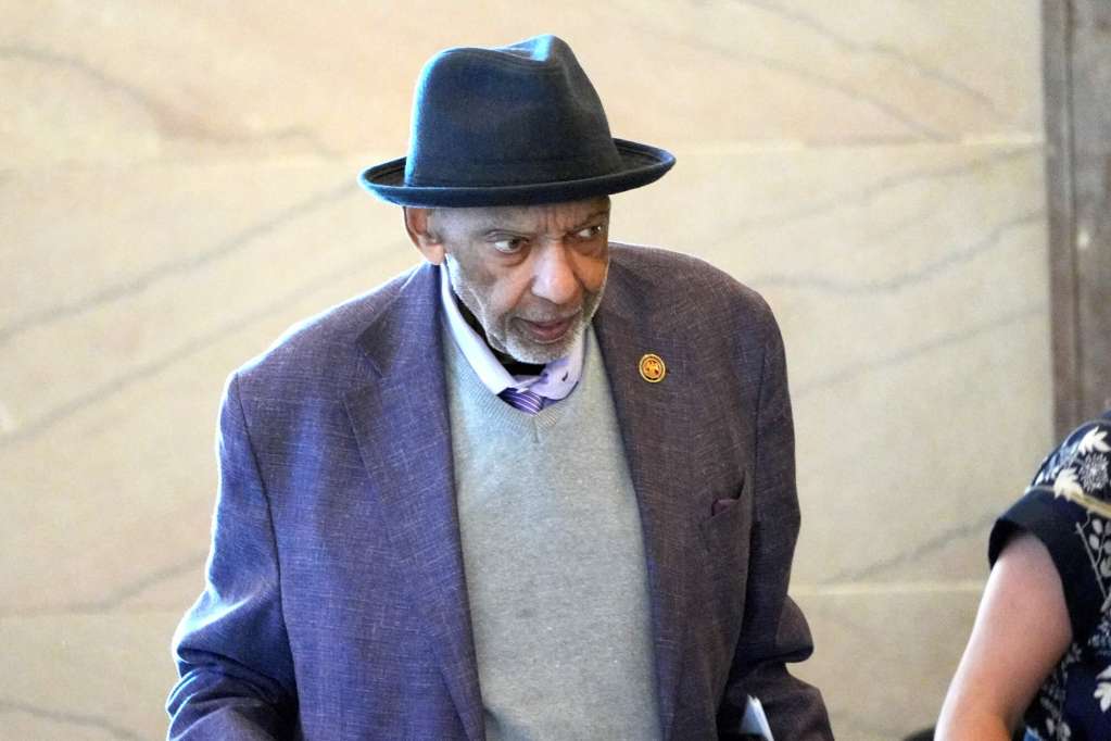 An overhead view of Bo Brown, waring a black hat and suit jacket, inside a building
