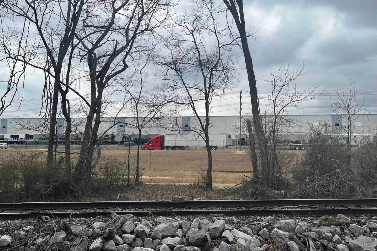 A data center can be seen past a railroad track and some trees