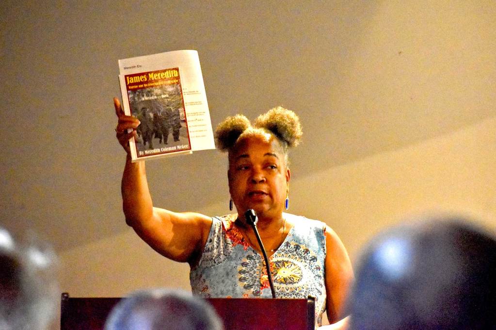 Meredith Coleman McGee holds up a copy of a book with the title James Meredith