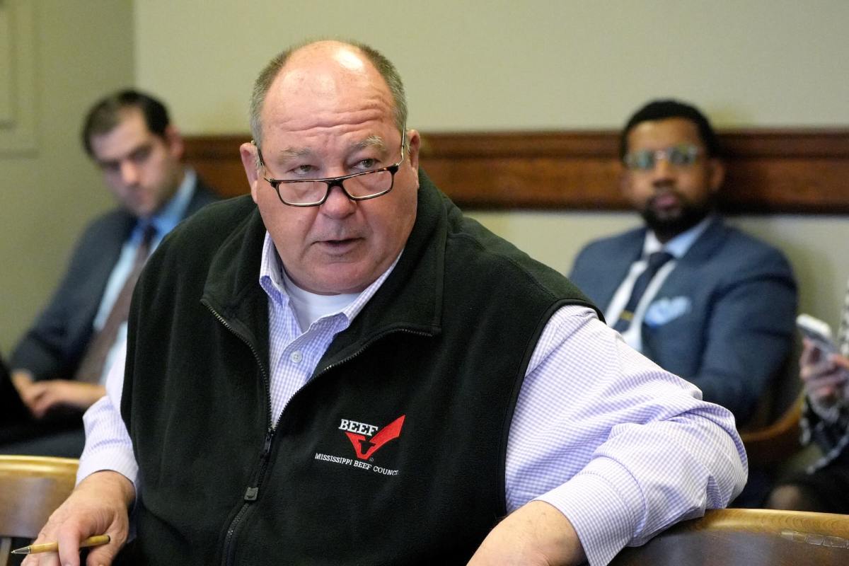 A closeup of Price Wallace in a committee meeting. He's wearing a black vest with a Mississippi Beef Council logo on the left breast.