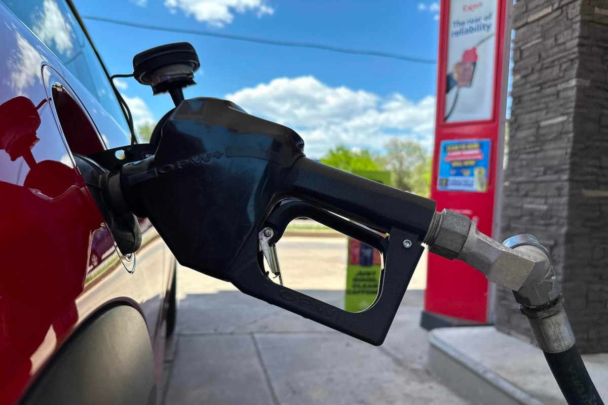 A close up of a gas pump inserted into a red car.