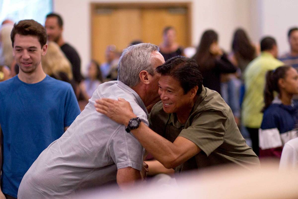 Two men hugging in a crowded room