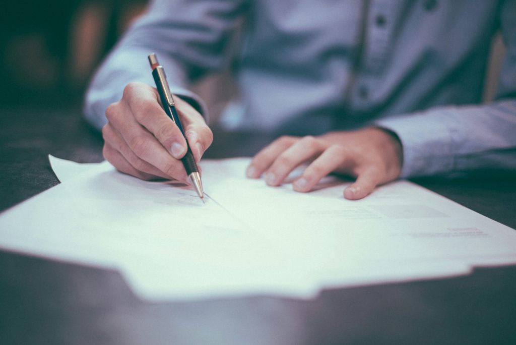 Closeup of a man writing on a sheet of paper at his desk